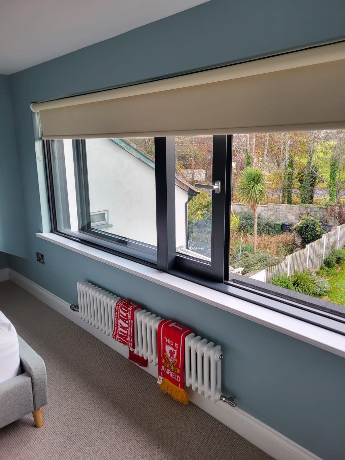 Roof window installation with dark frame and garden view
