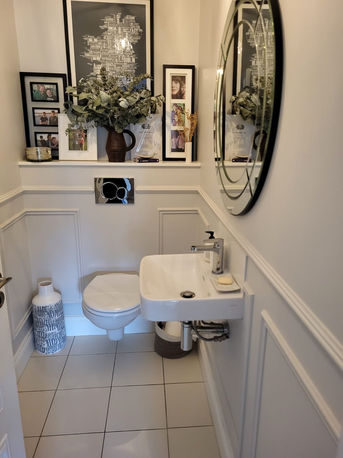 Elegant bathroom with dark floral wallpaper, green vanity, brass mirror, and white toilet