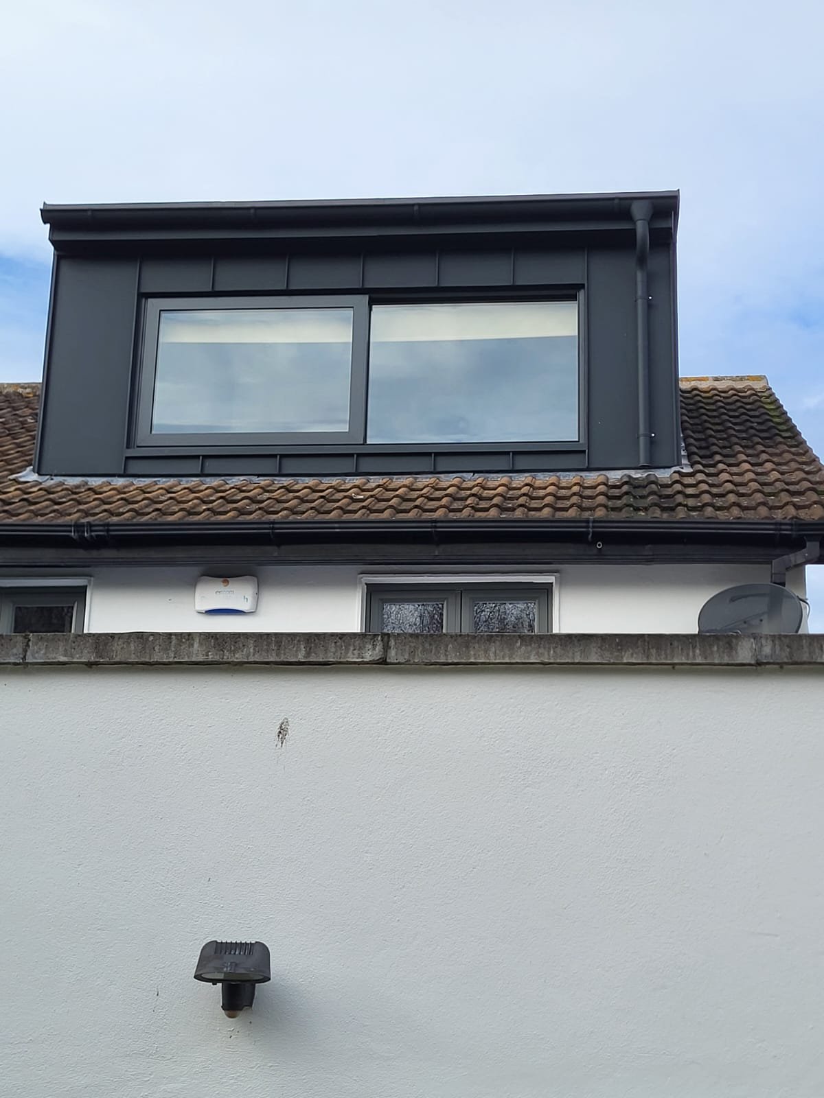Modern house exterior with white render, black-framed windows, and dark roof