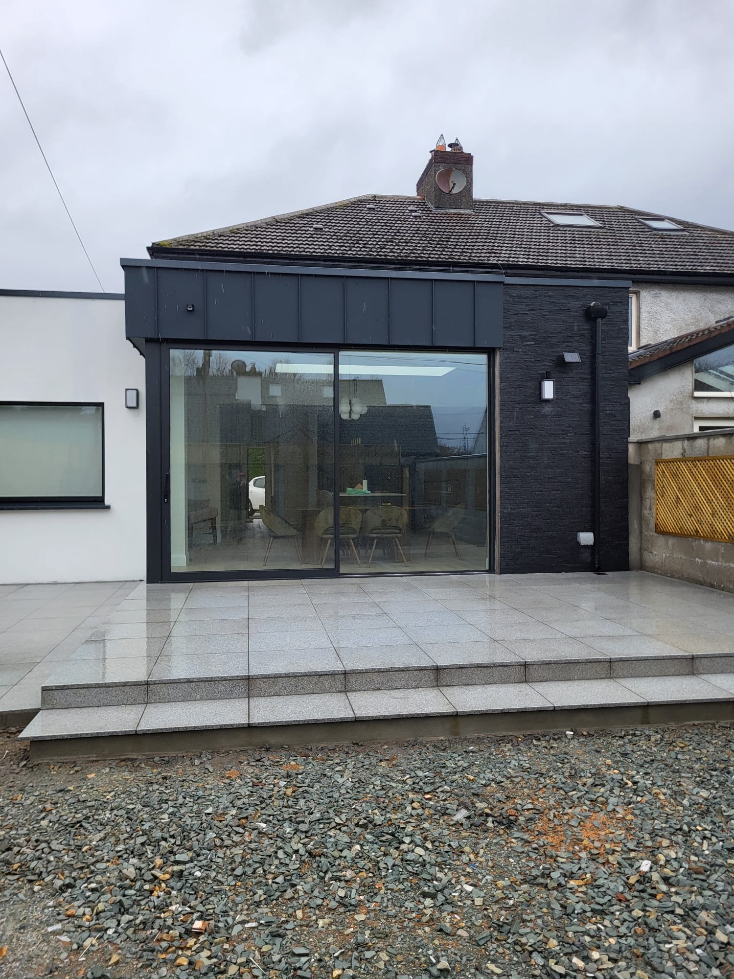 Modern house extension exterior with large black-framed glass doors and patio