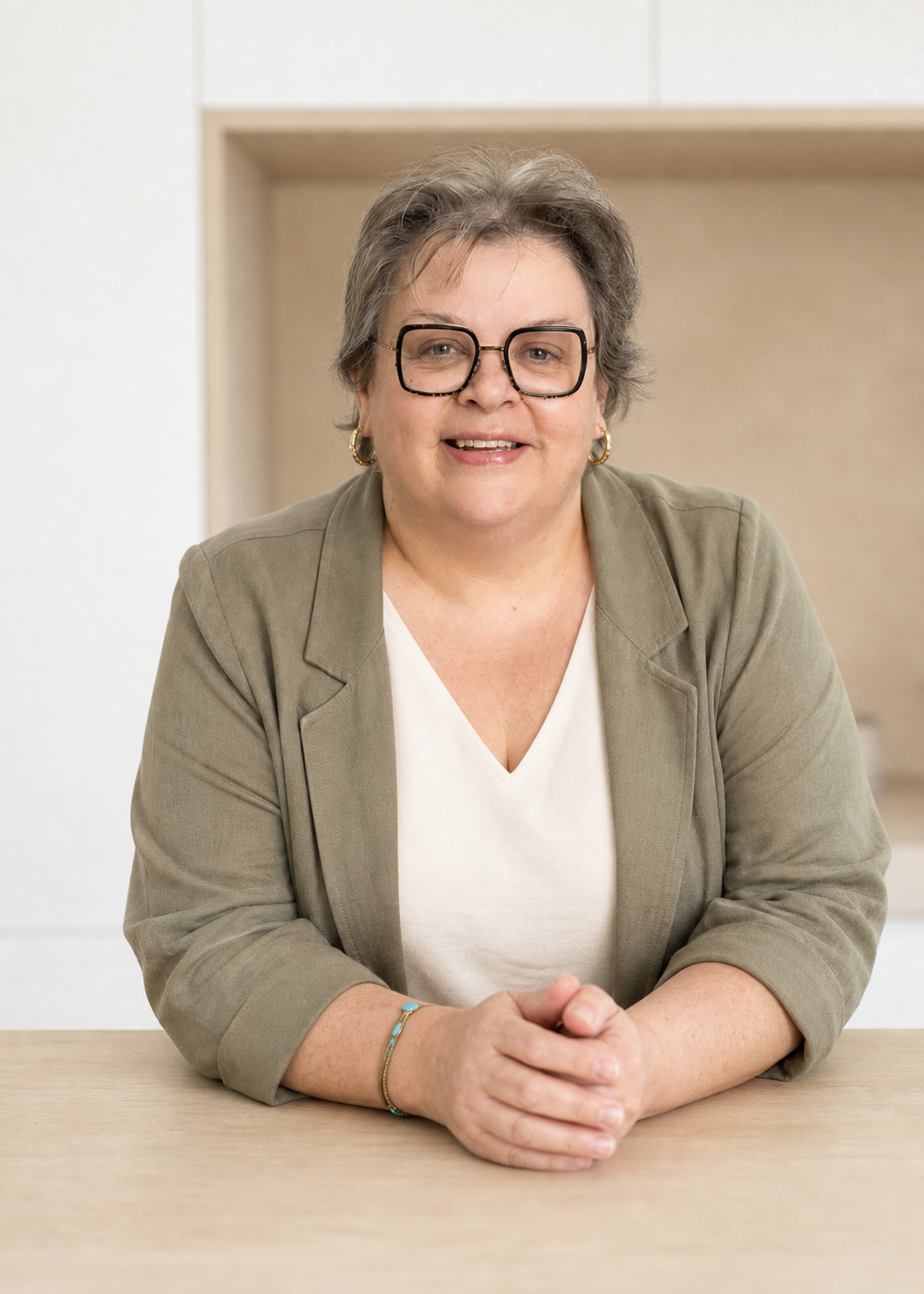 Portrait professionnel de Séverine Lion souriante, portant des lunettes et un pull noir avec motifs violets, fond en bois naturel