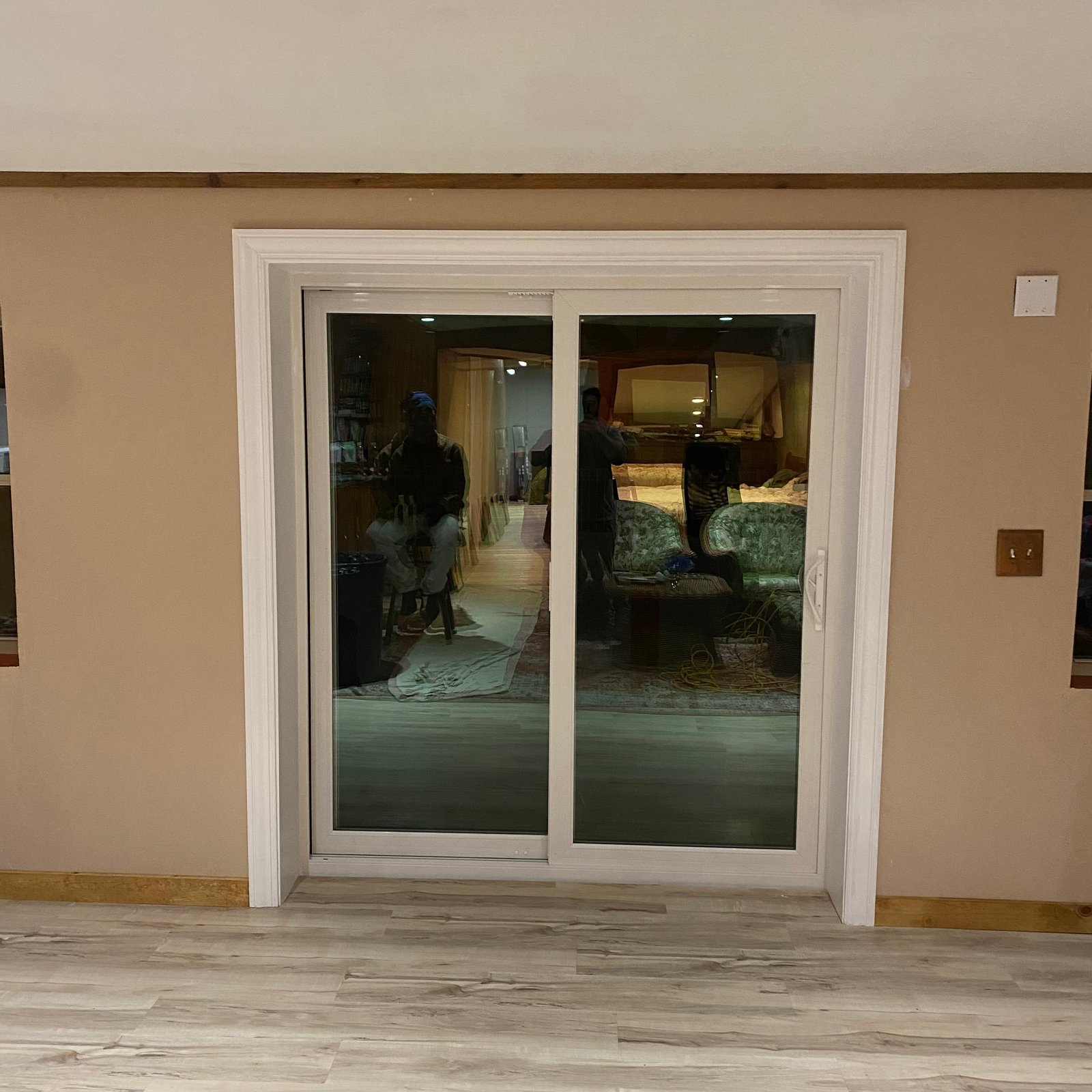 White-framed sliding glass patio door installed in a finished interior room with light wood flooring