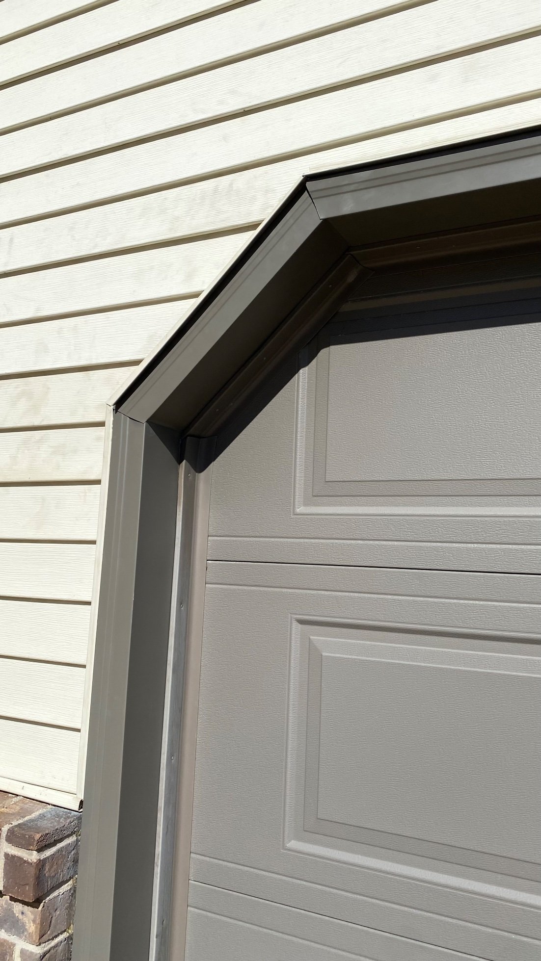 Close-up of bronze garage door trim along the top edge of a gray garage door.