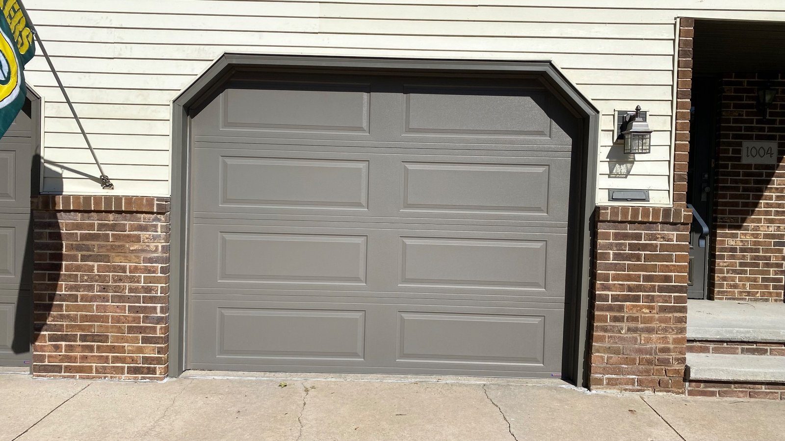 Bronze garage door trim on a gray garage door between brick columns.