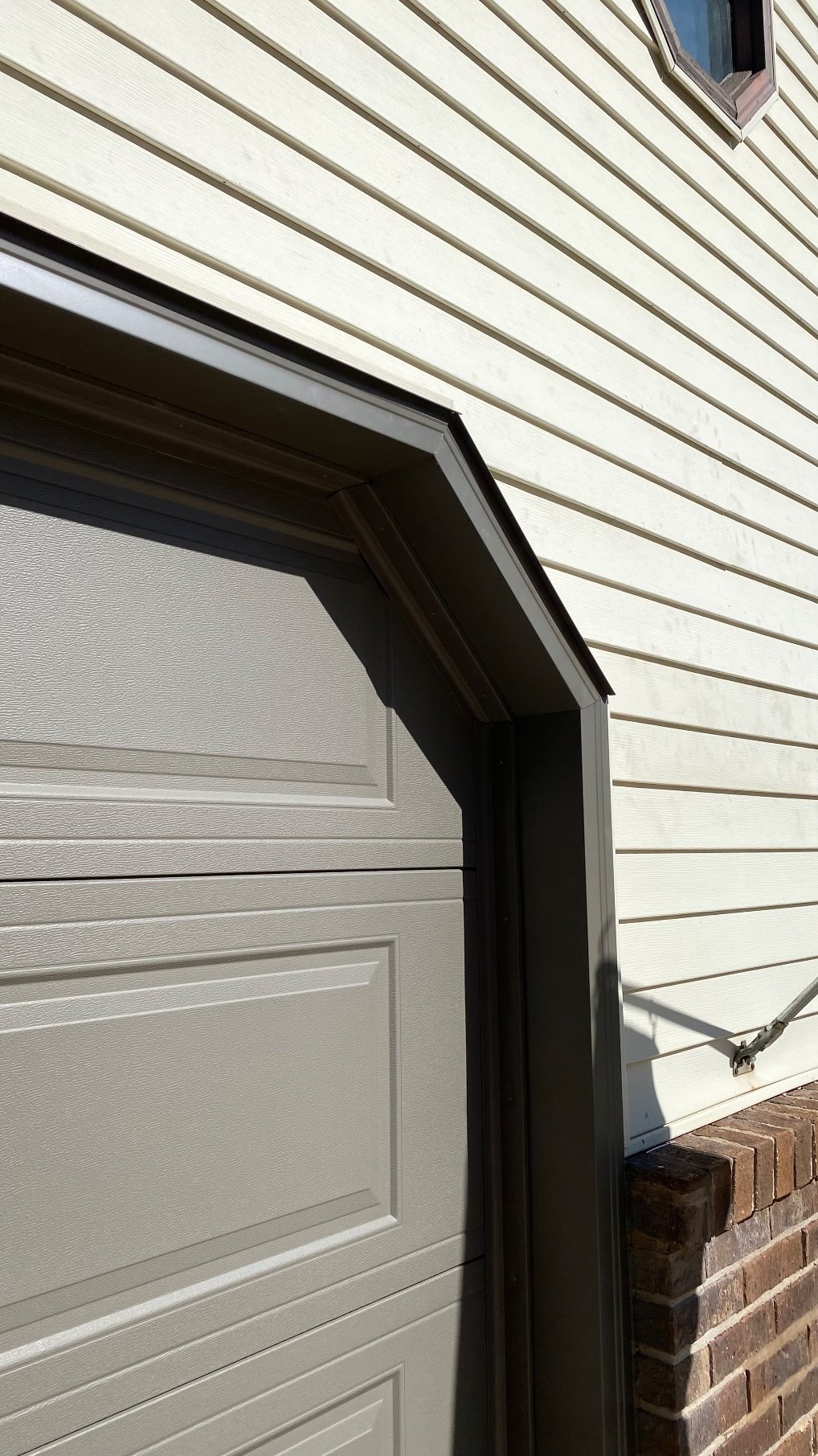 Close-up of bronze garage door trim at the upper right corner of a gray garage door.