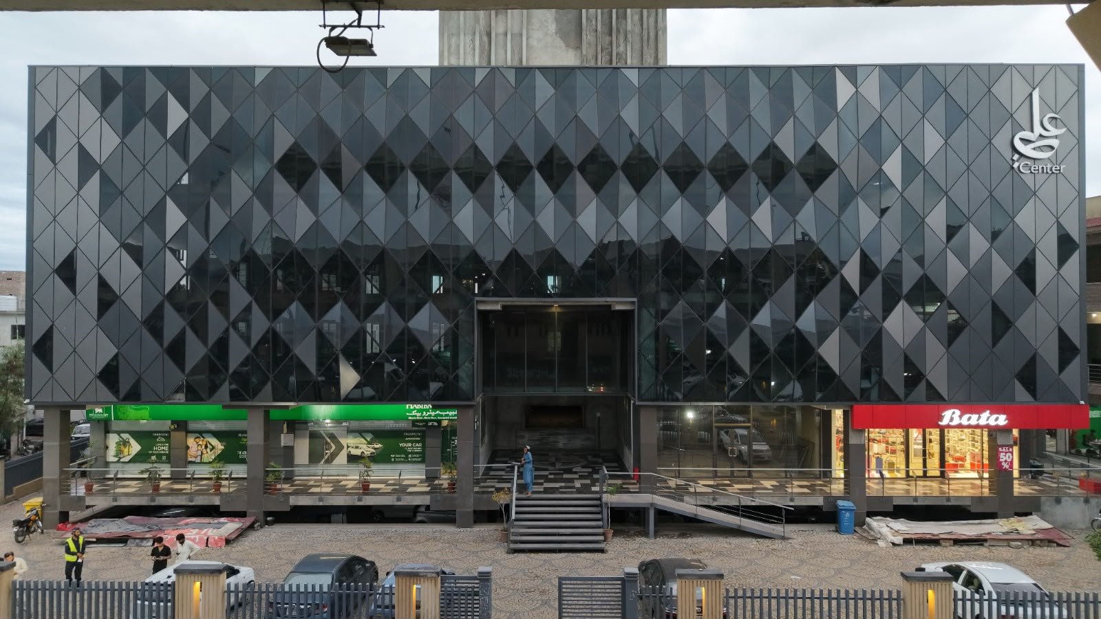 Full front elevation of the Ali Center dark diamond-grid glass facade with Bata storefront