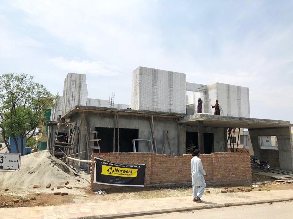 Worker walking past a brick boundary wall at the house construction site