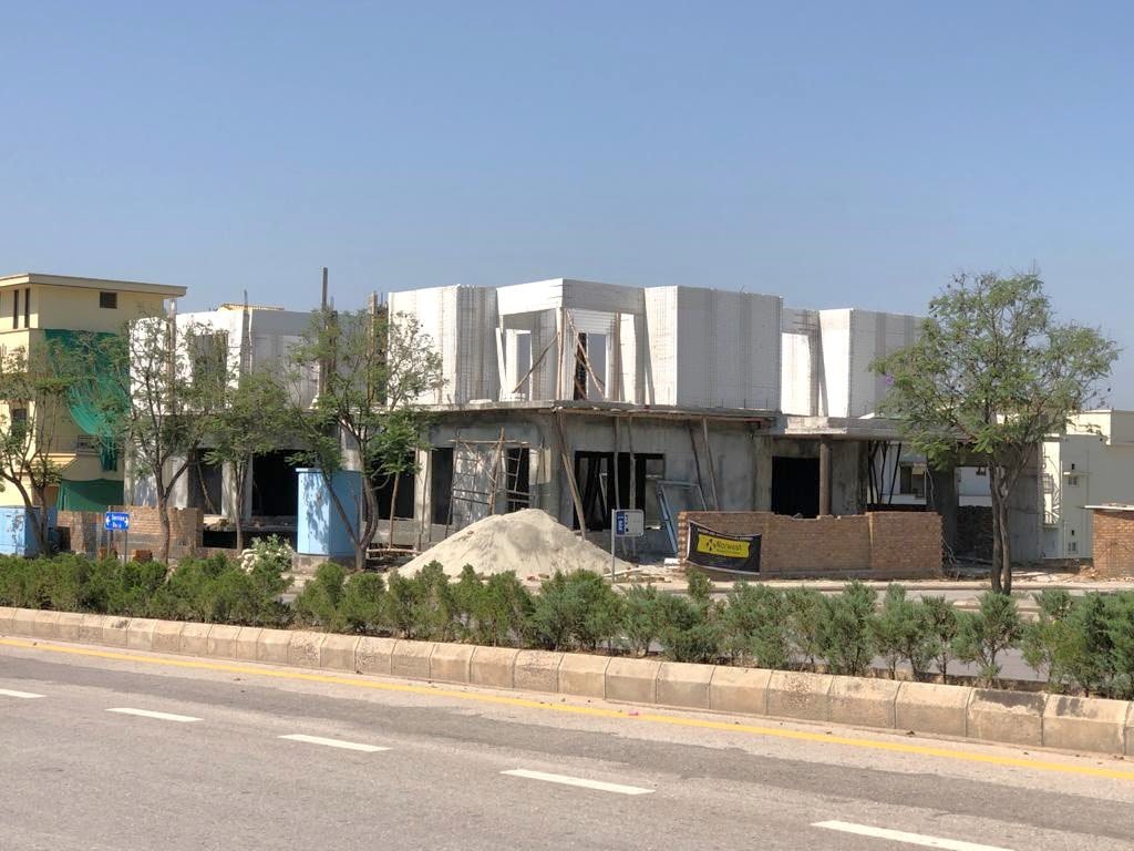Street view of a house with white mesh upper walls during construction