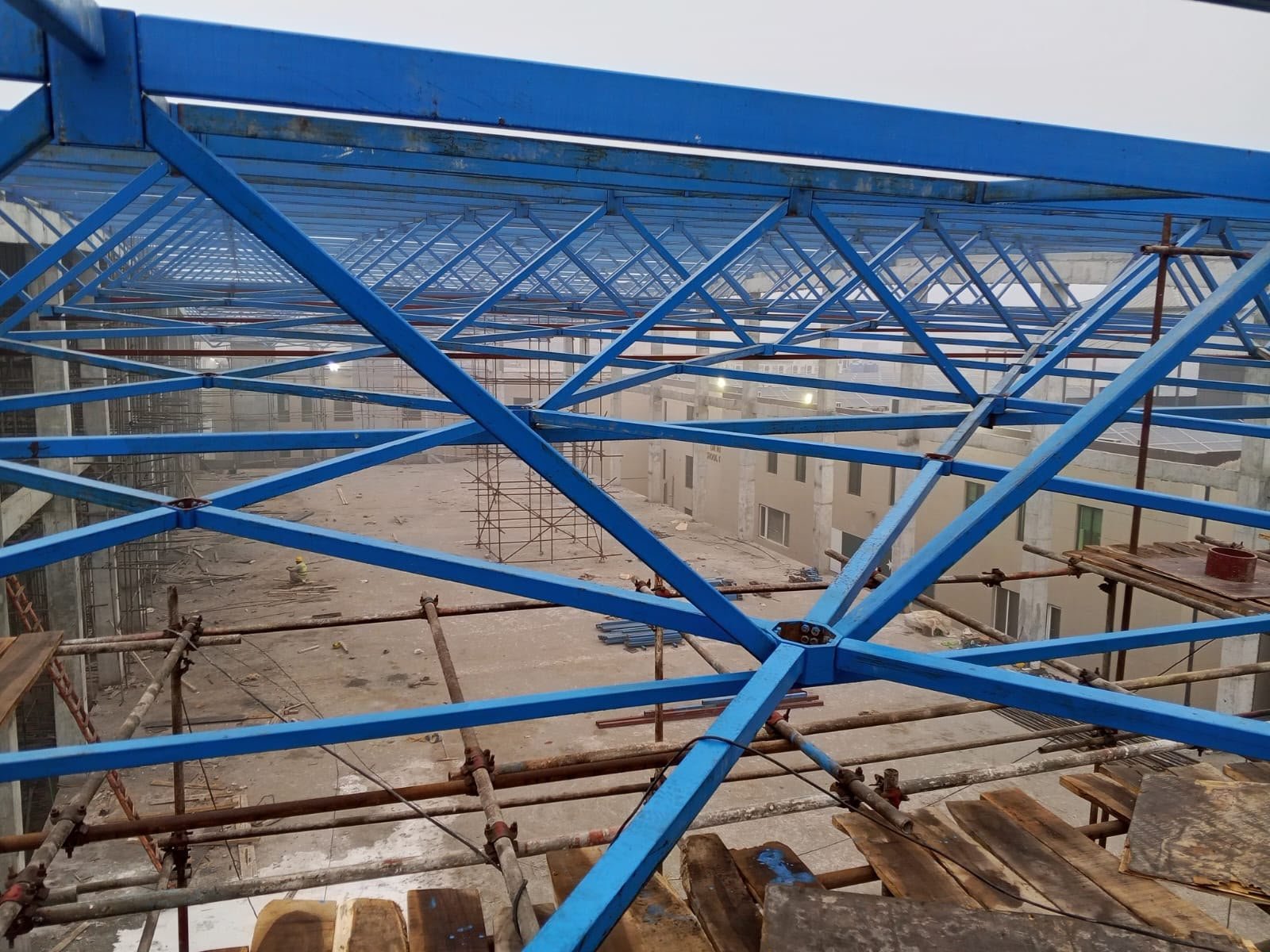 Close view of intersecting blue steel free-form roof trusses over the site