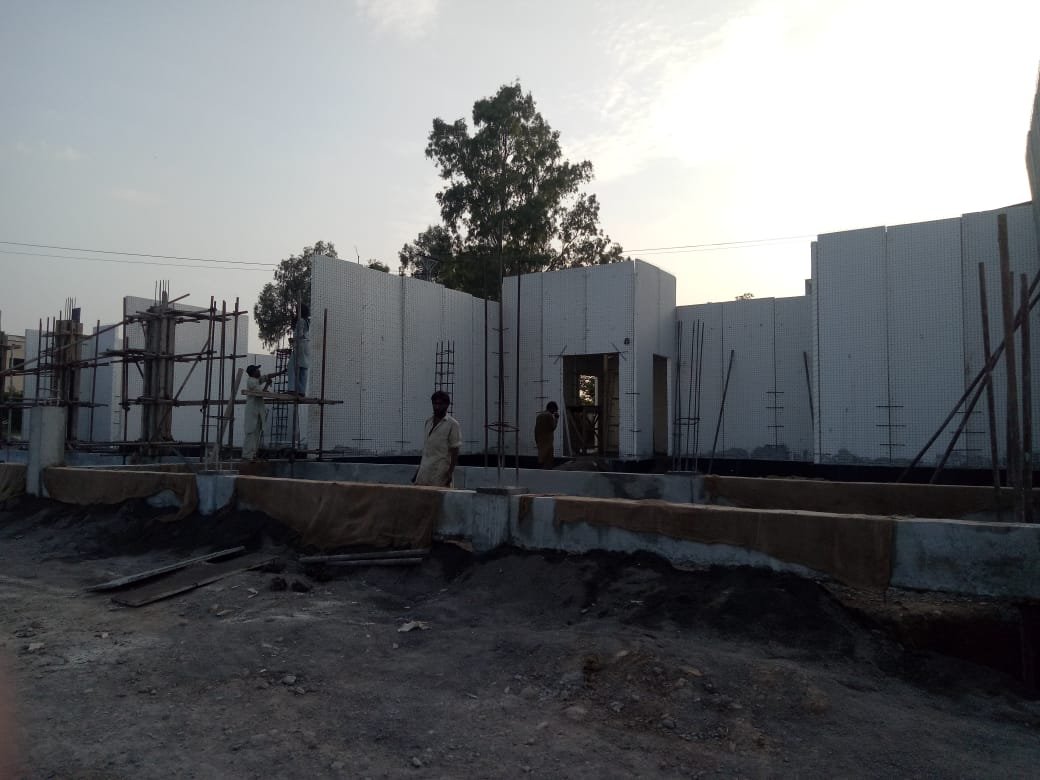 Crew erecting white insulated wall panels on a house foundation