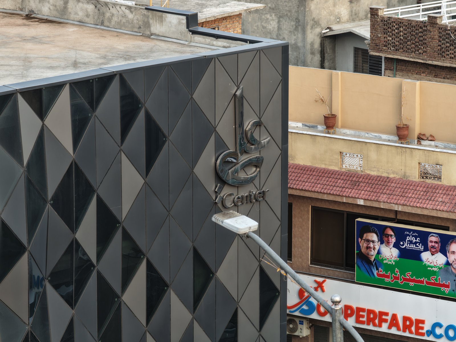 Ali Center metallic calligraphic logo mounted on dark diamond panel facade