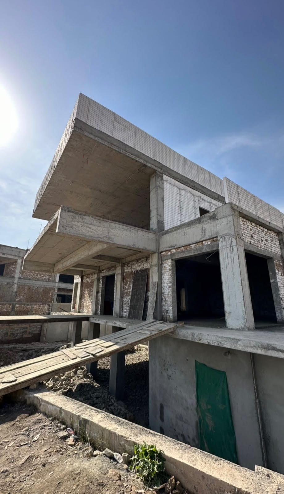 Concrete farmhouse frame with open bays and a timber access ramp