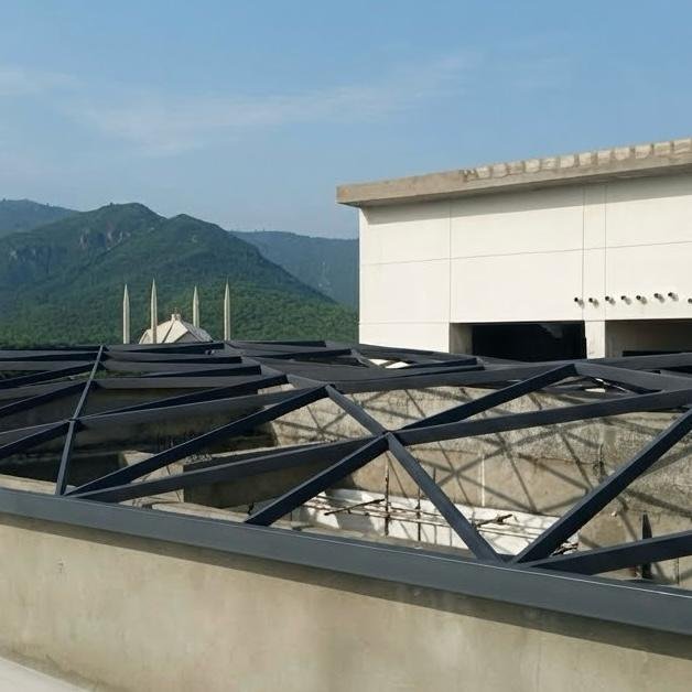 Steel grid shell frame on a rooftop with mountains and minarets beyond