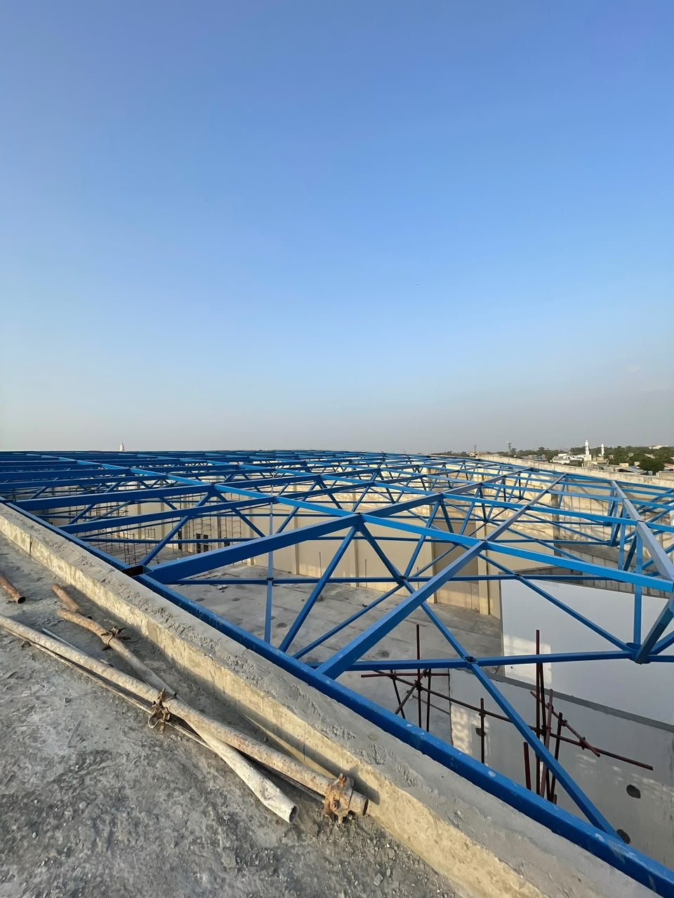 Blue steel free-form roof lattice on a rooftop against a clear sky