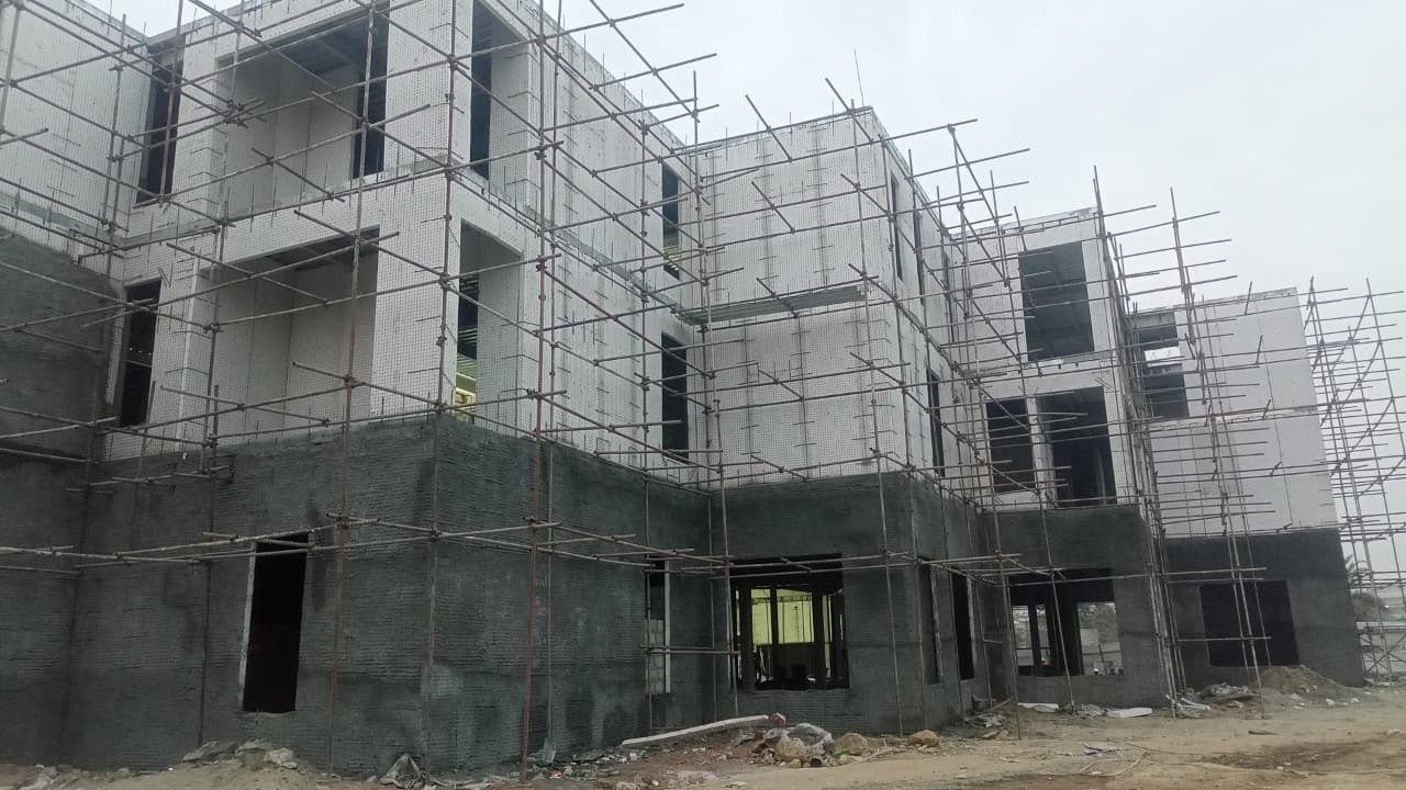 Multi-story steel and SCIP building under scaffolding with white upper floors and grey base in Rawalpindi