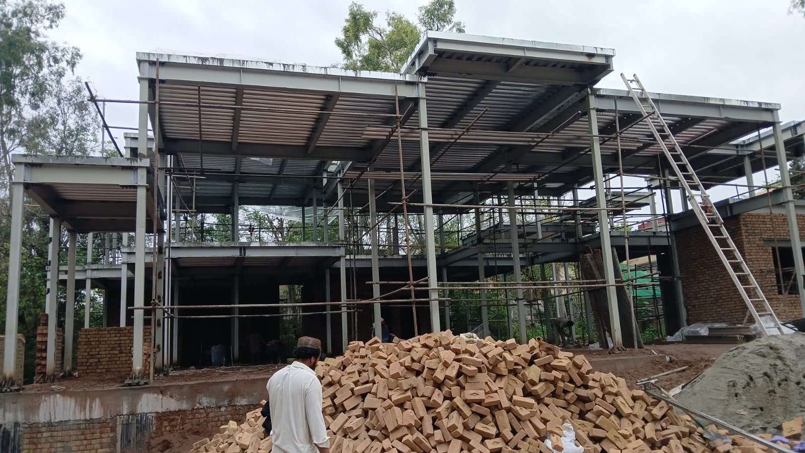 Steel frame and decking stage with brick stockpile during SCIP construction in Islamabad