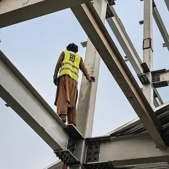 Construction worker inspecting elevated steel beams