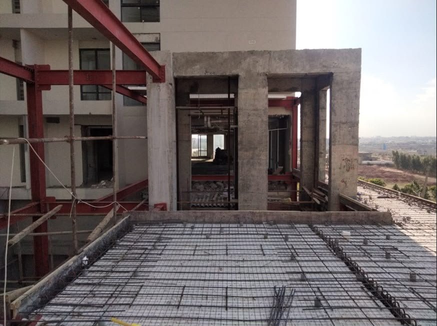 Roof deck reinforcement mesh beside a concrete frame and red steel