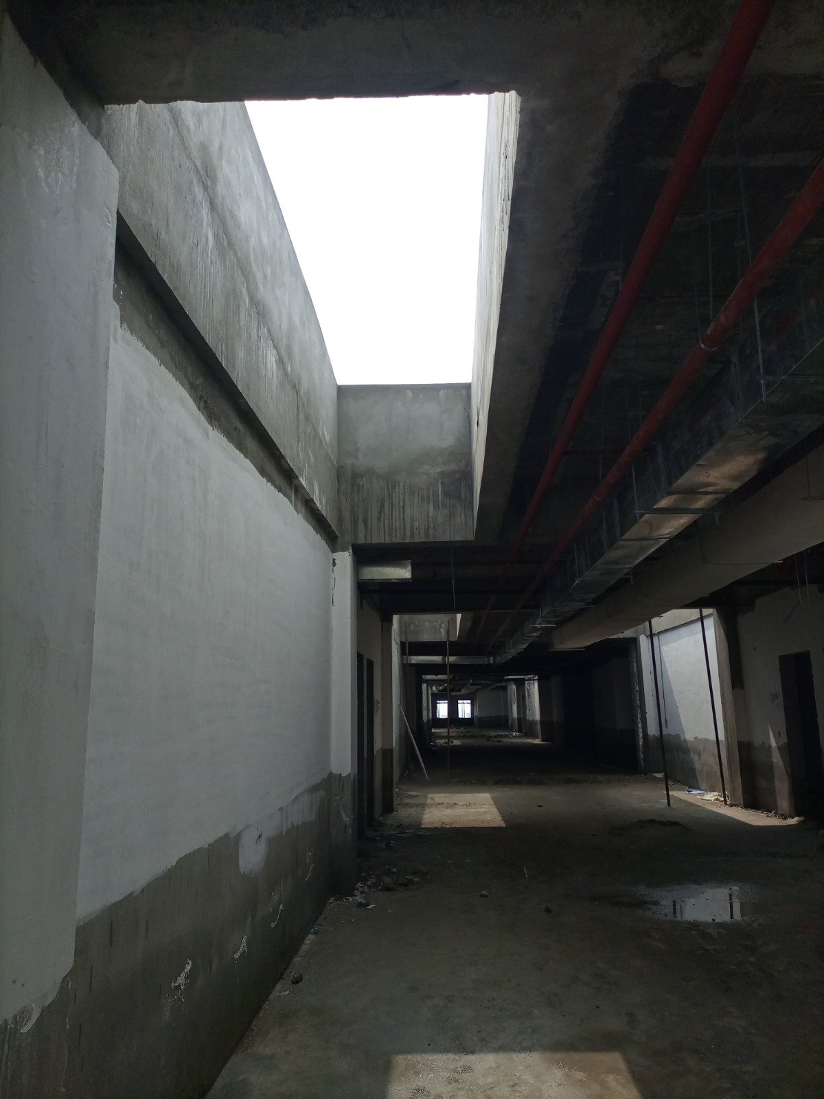 Daylight entering an unfinished concrete interior through a rectangular roof opening