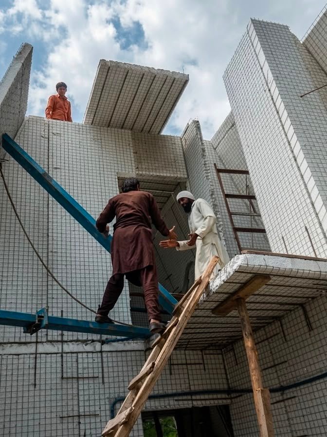 Workers assembling SCIP mesh panels on the Snow Pines A-frame structure in Murree