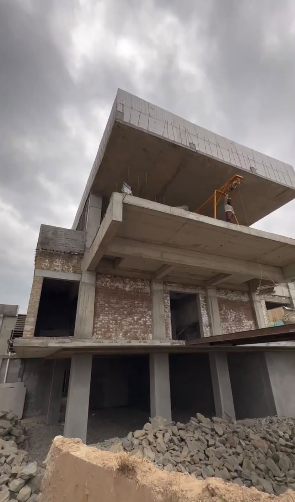 Worker on a hoist beneath the cantilevered roof of the farmhouse frame