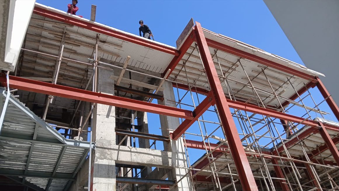 Crew standing on red steel beams and decking against a clear sky