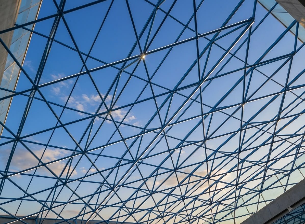 Glazed blue steel free-form roof lattice against a clear sky