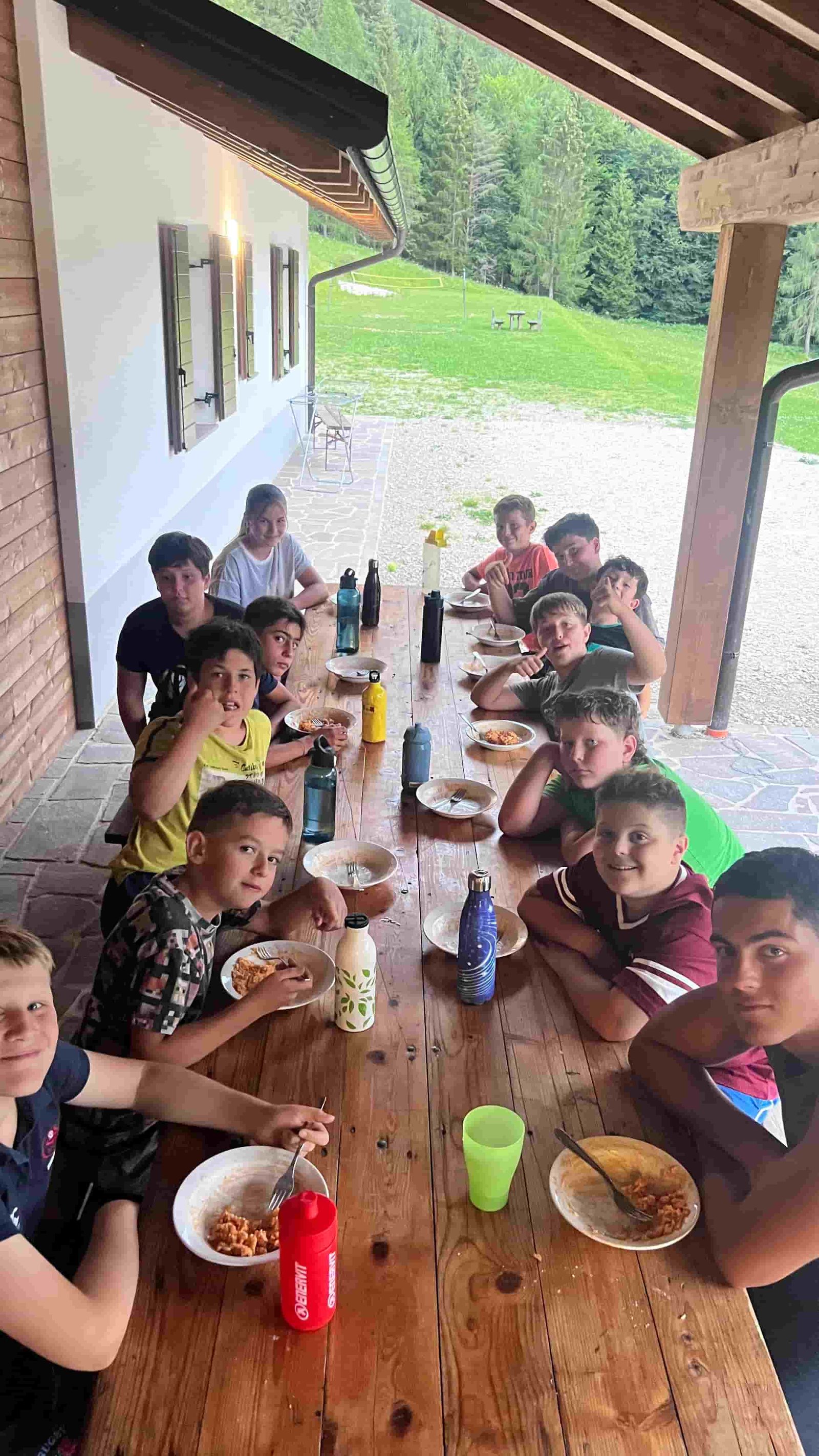 Il pranzo del gruppo al lungo tavolo di legno sotto il portico