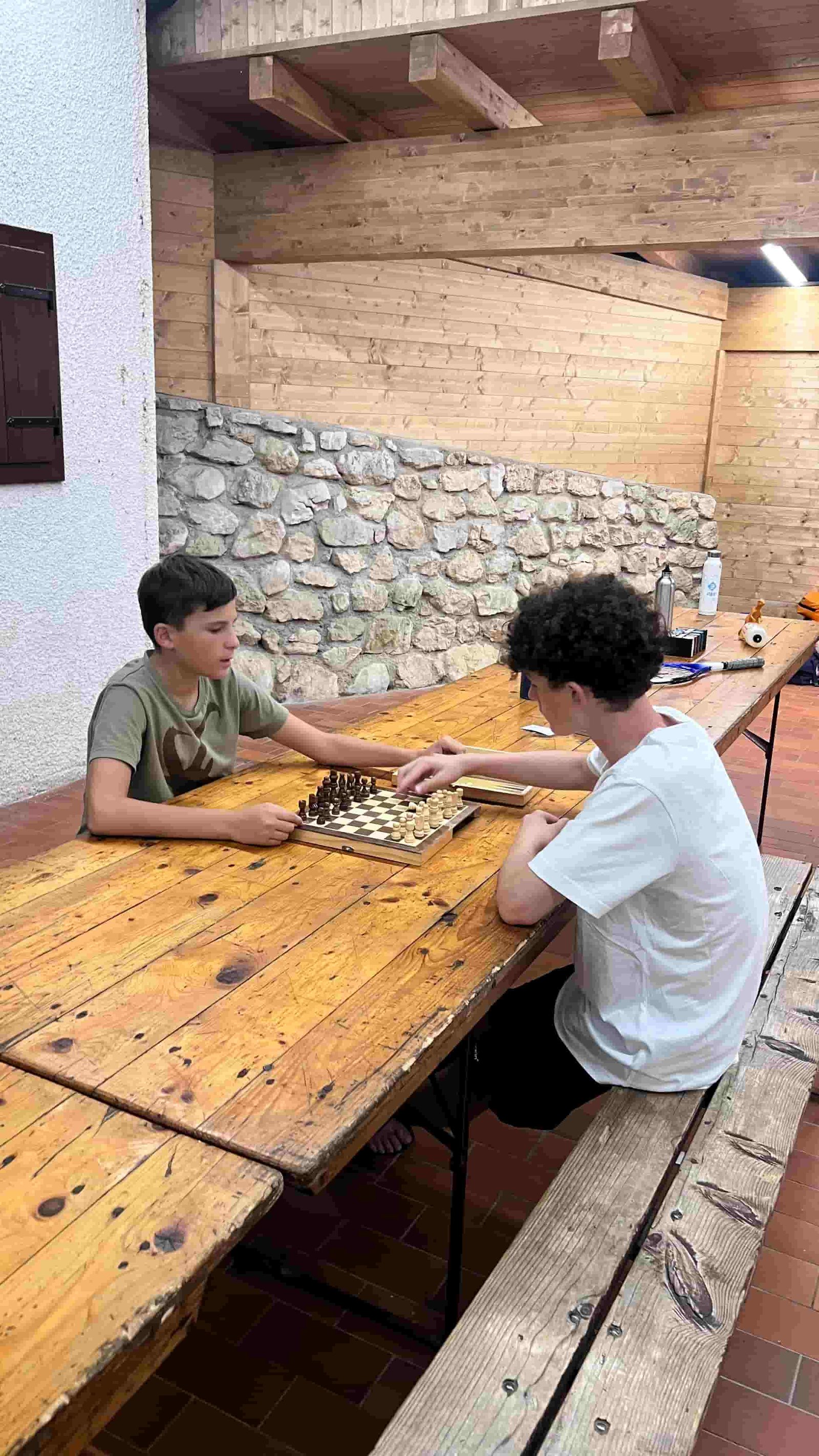 Due ragazzi che giocano a scacchi al tavolo di legno sotto il portico