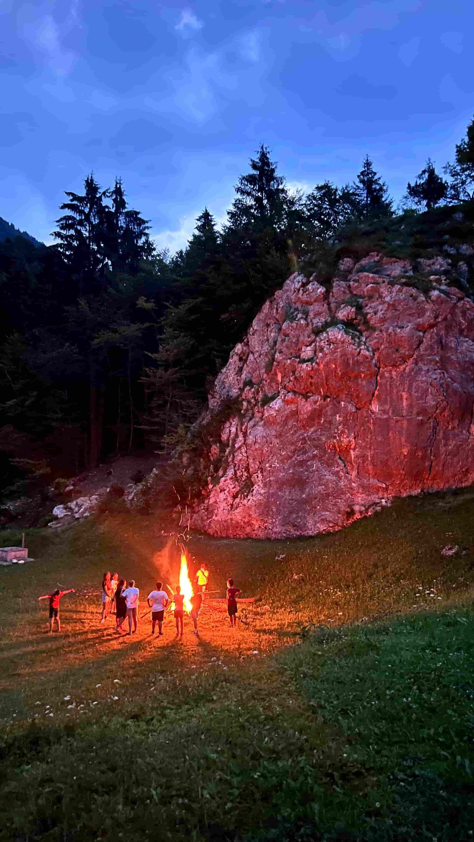 Il falò serale che illumina la roccia con il gruppo raccolto intorno