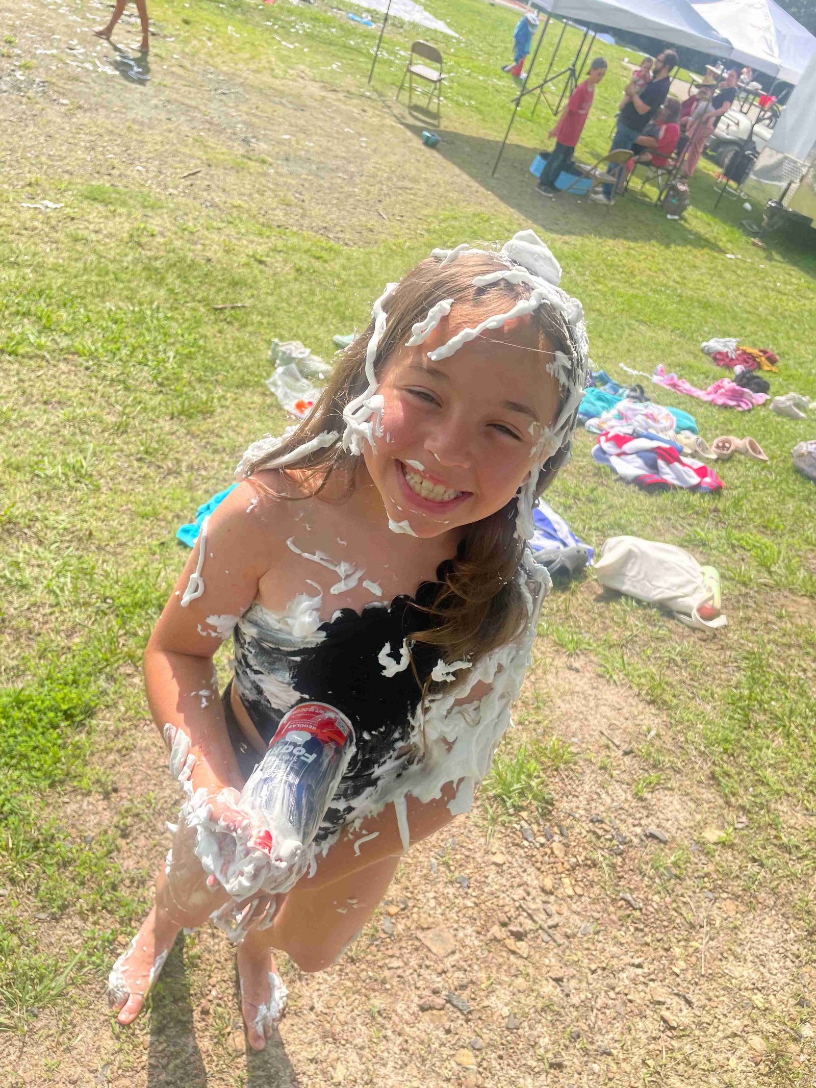 Girl covered in shaving cream from messy outdoor game
