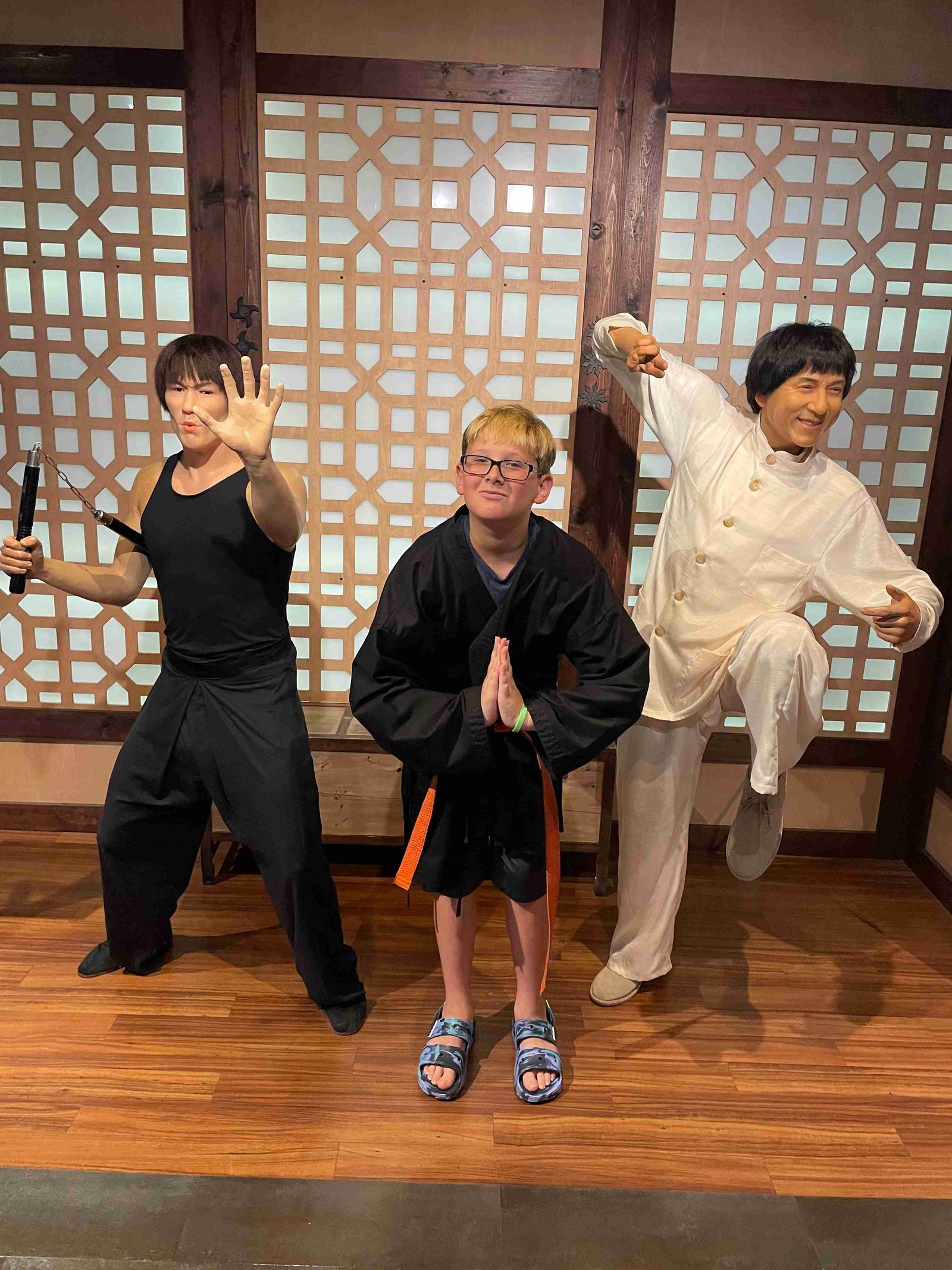 Boy posing with Bruce Lee and Jackie Chan wax figures