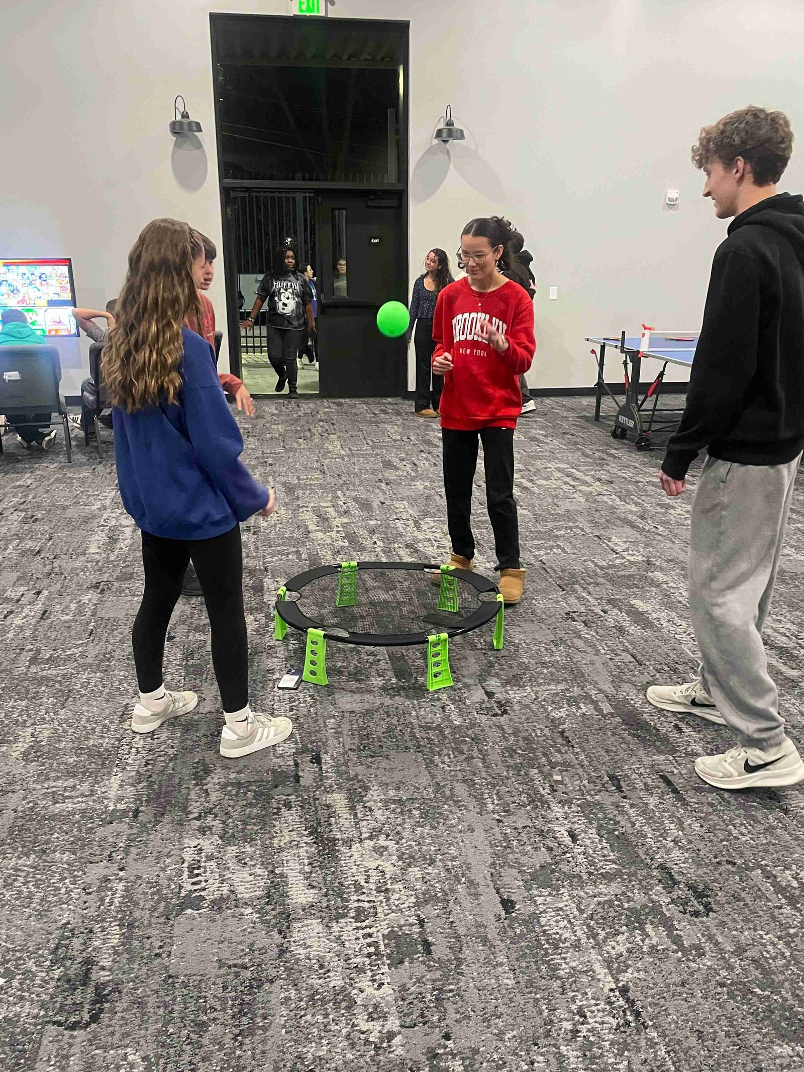 Teenagers playing a spikeball game indoors