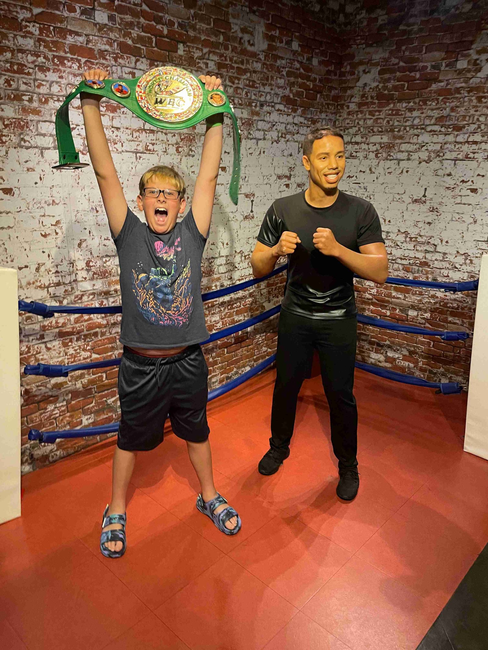 Boy holding championship belt posing with Tiger Woods wax figure