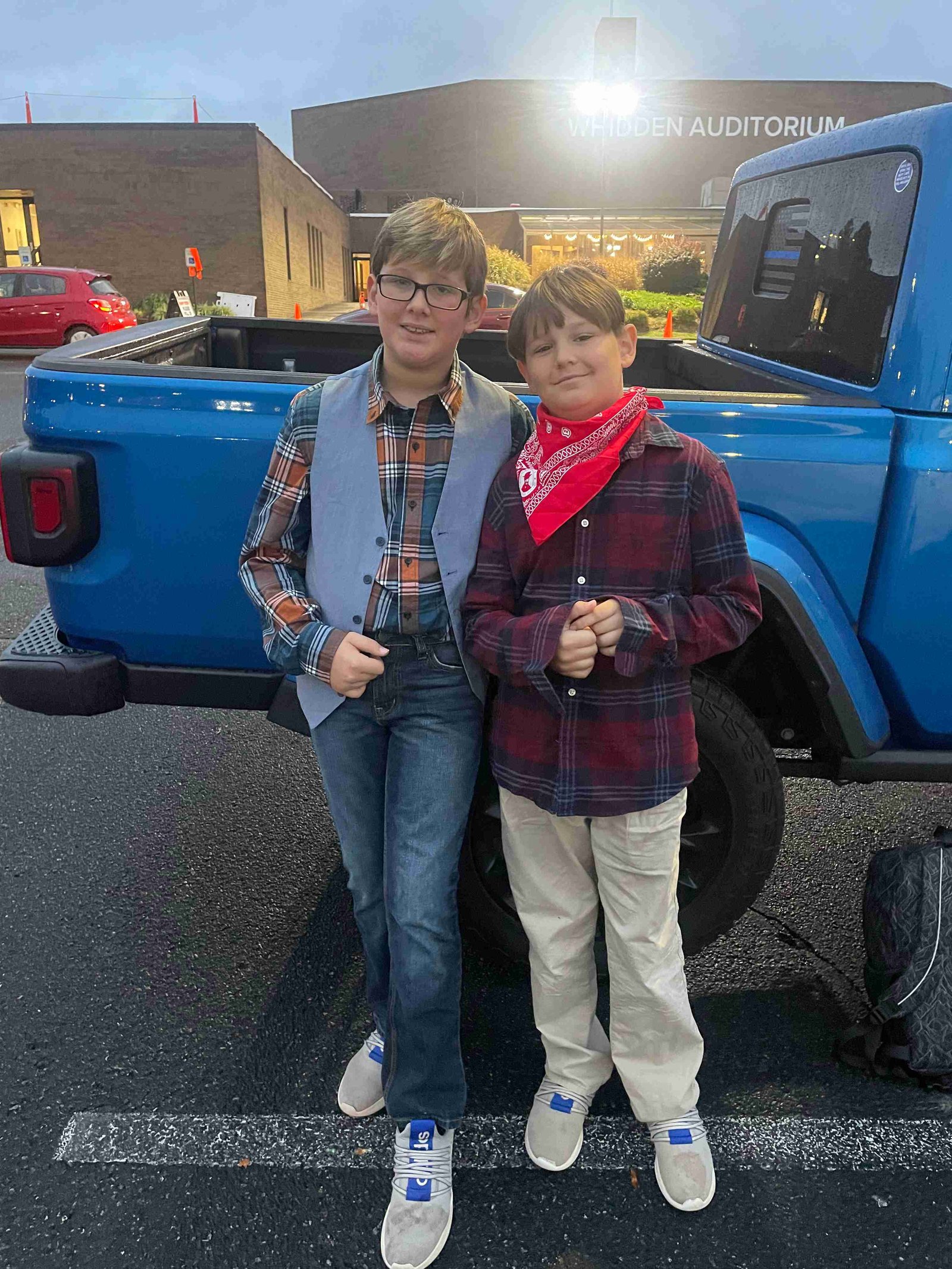 Two young boys smiling by a blue truck