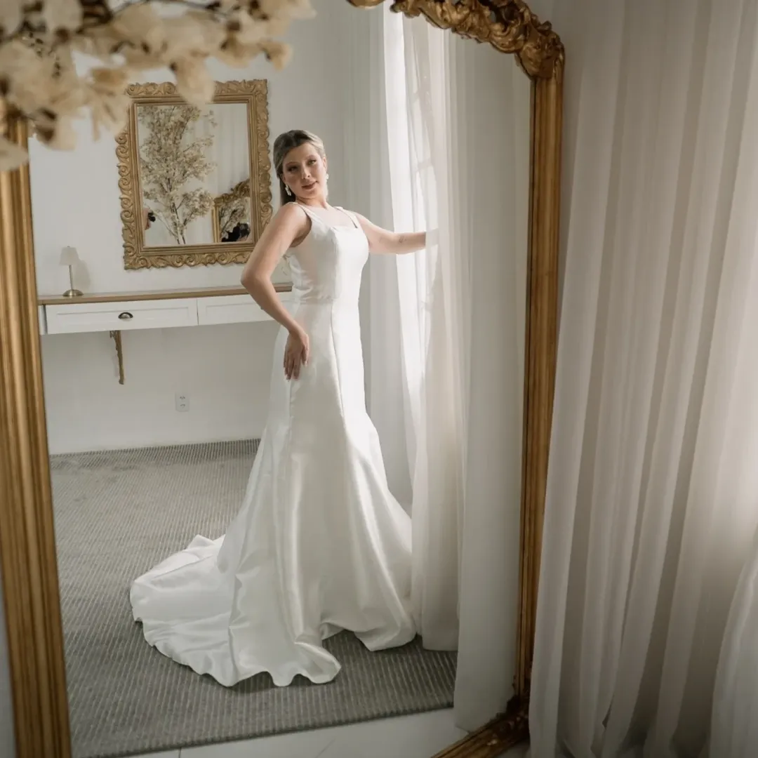 Noiva em vestido semi sereia branco com cauda em quarto elegante com espelho dourado