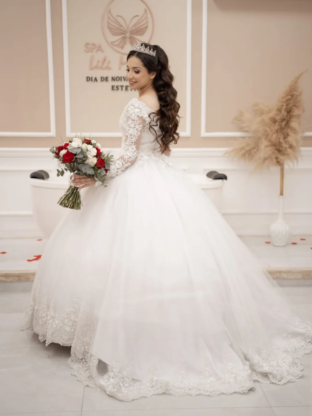 Noiva em vestido clássico com renda e buquê vermelho e branco em salão elegante