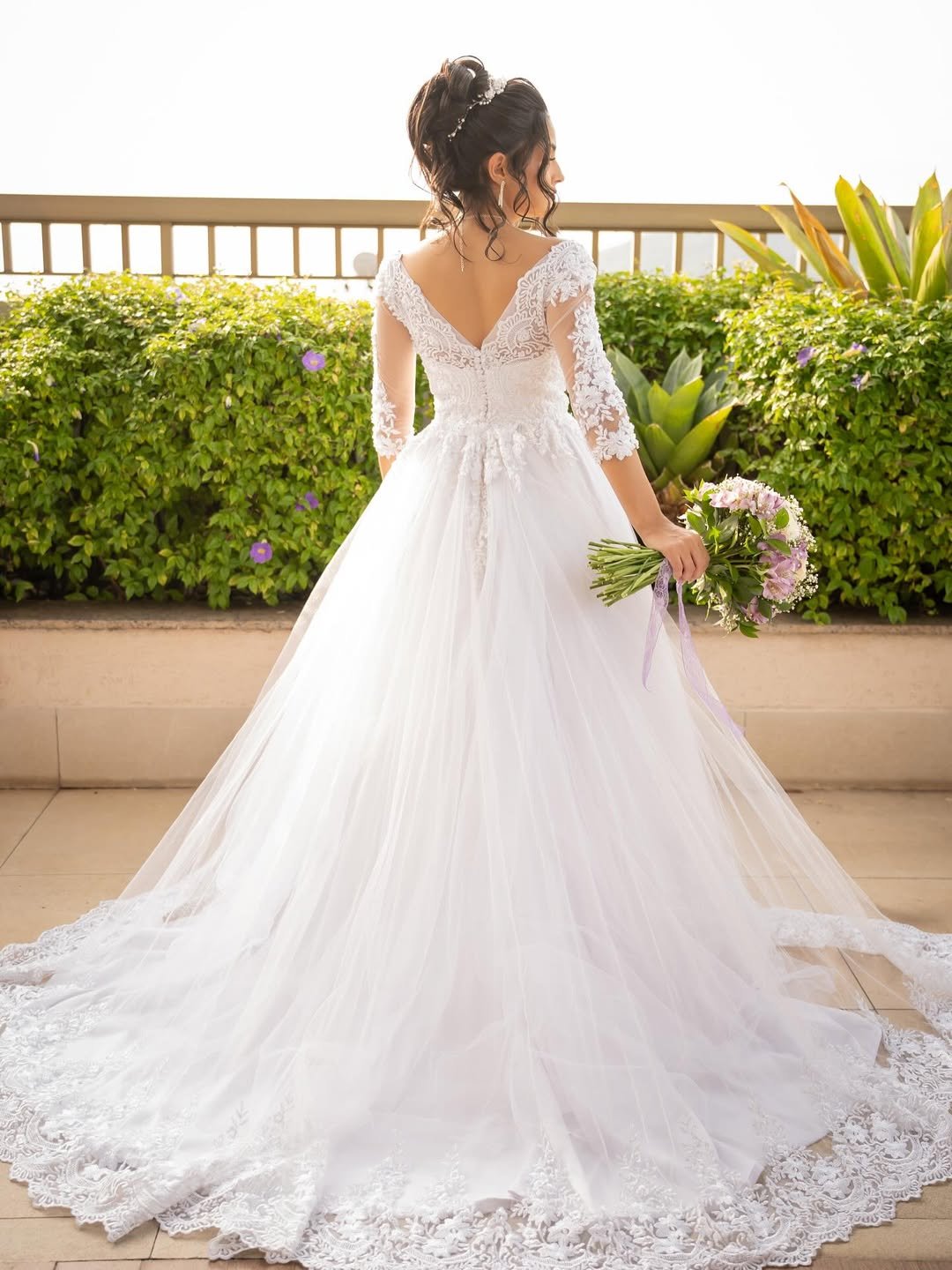 Noiva em vestido princesa com renda e cauda em varanda com plantas