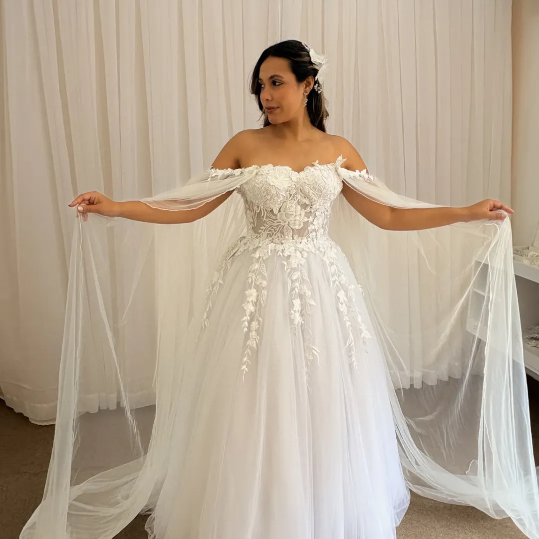 Noiva em vestido fluído com detalhes em renda e cauda longa em quarto elegante