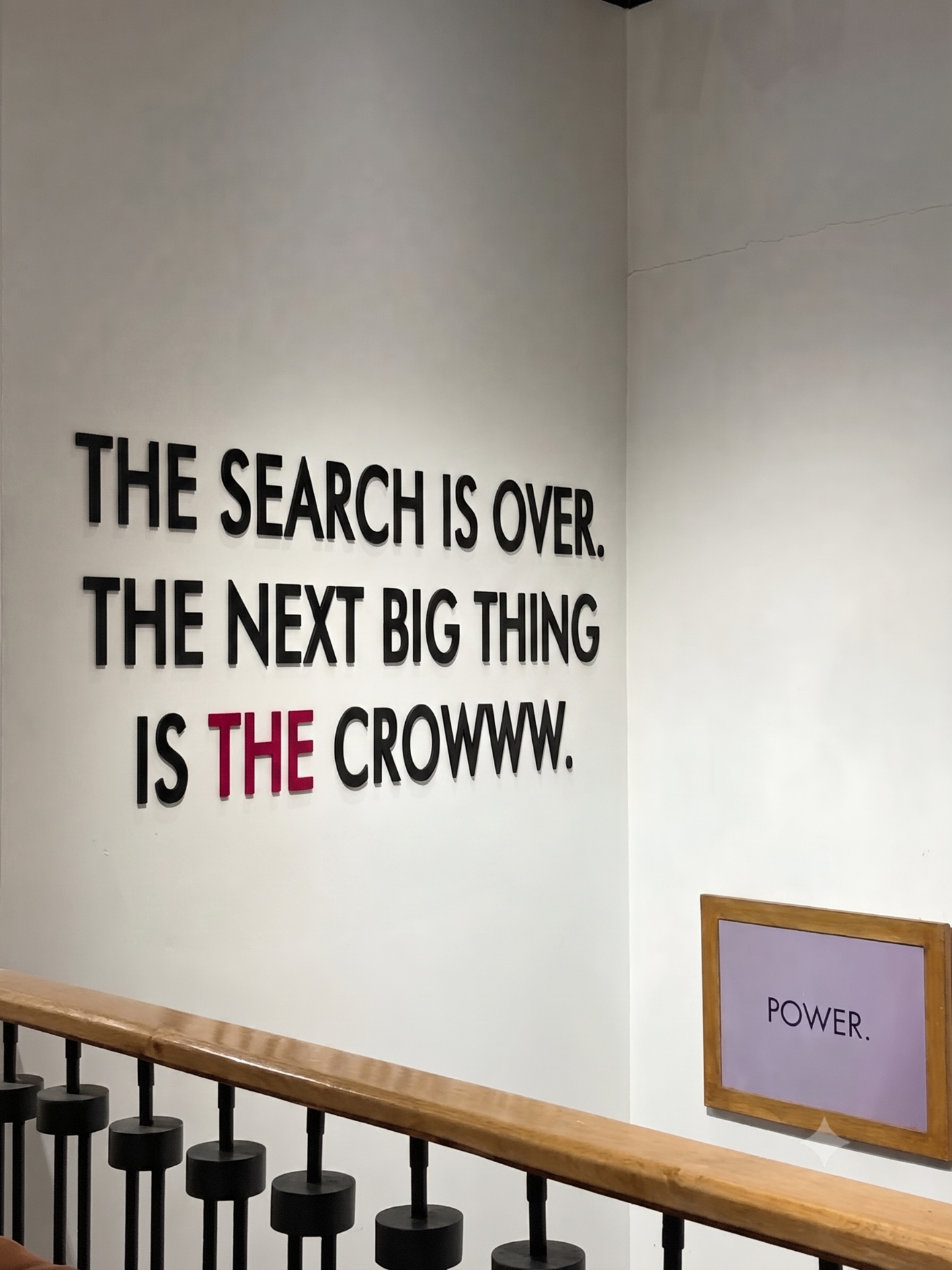 Wall installation reading THE SEARCH IS OVER. THE NEXT BIG THING IS THE CROWWW. with THE in crimson and a framed POWER. sign
