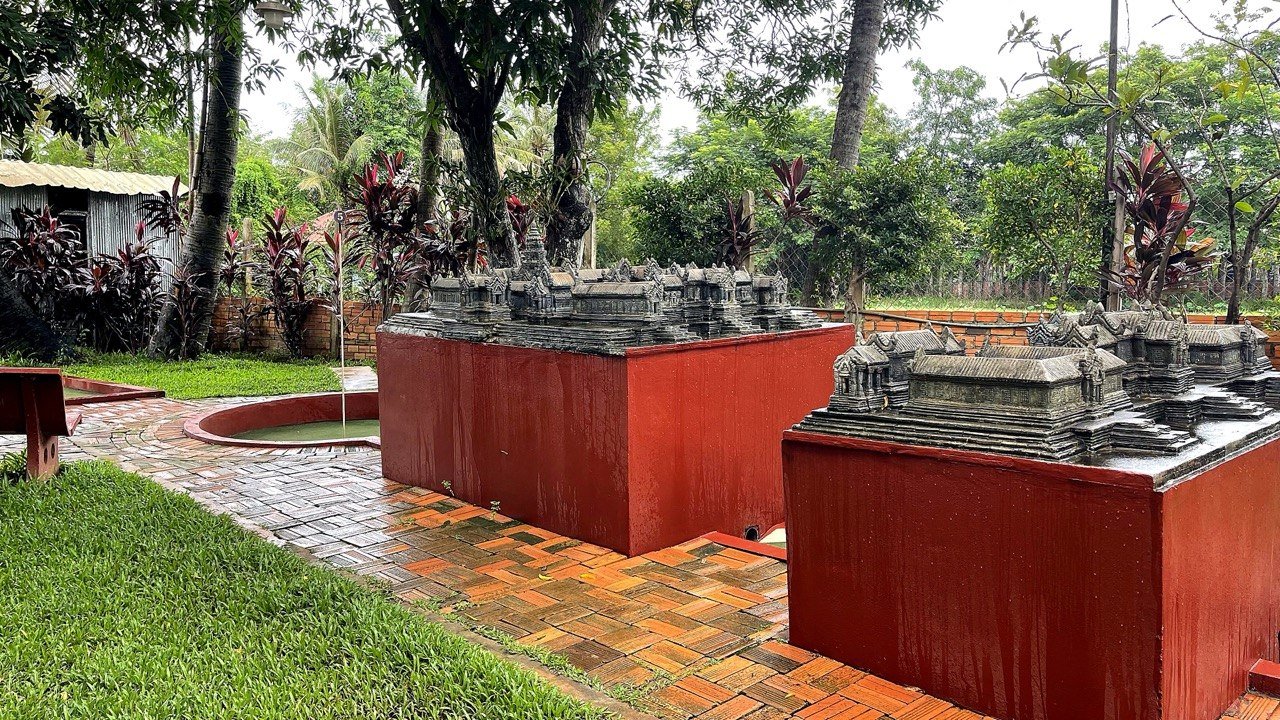 Temple replica display with red platforms and garden setting