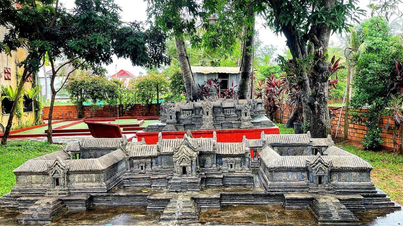 Detailed temple replica with intricate Khmer stone carvings in garden setting