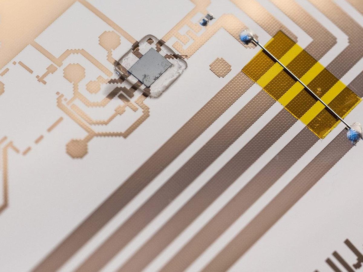 In-line digital soldering production line processing printed circuit board assemblies on a conveyor under pulsed-light modules
