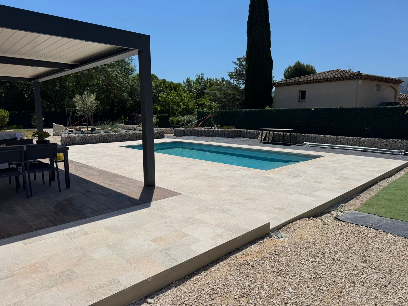 Pergola bioclimatique moderne avec structure noire et lames blanches, espace repas