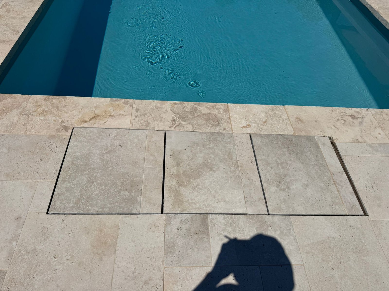 Vaste terrasse en pierre entourant la piscine avec aménagements paysagers soignés