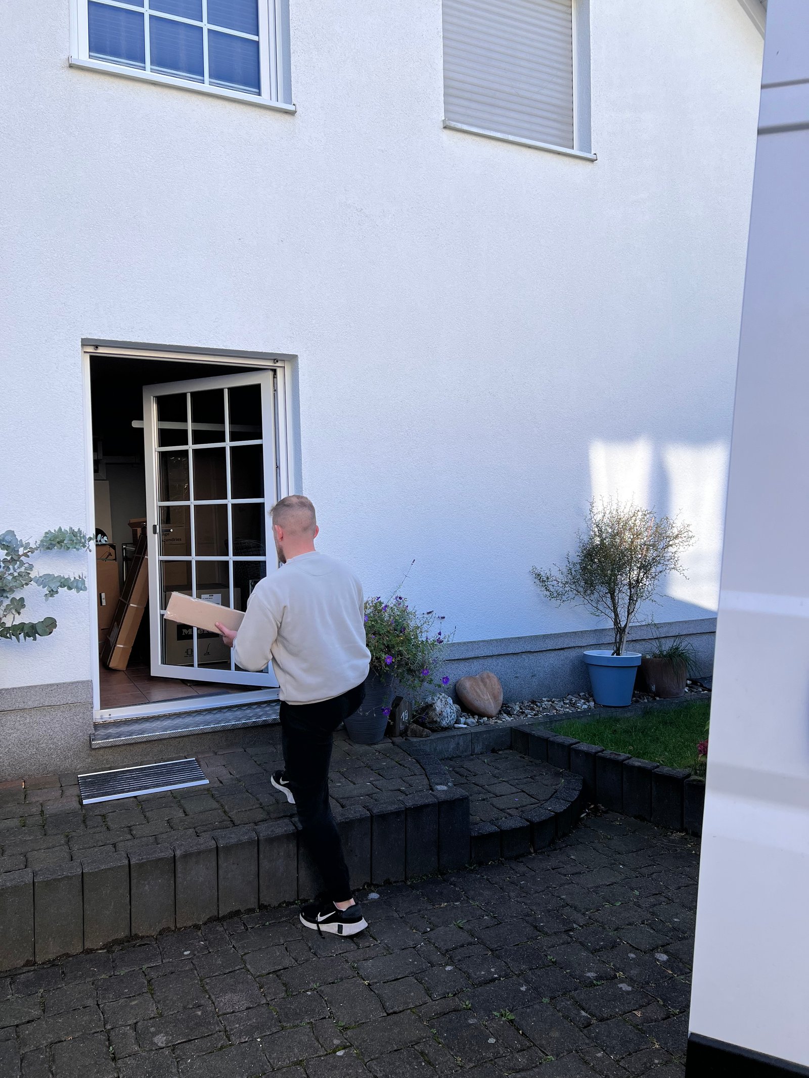 Eigene Aufnahme: TRAILERO-Mitarbeiter trägt ein Möbelstück aus einem Wohnhaus zur Anlieferung