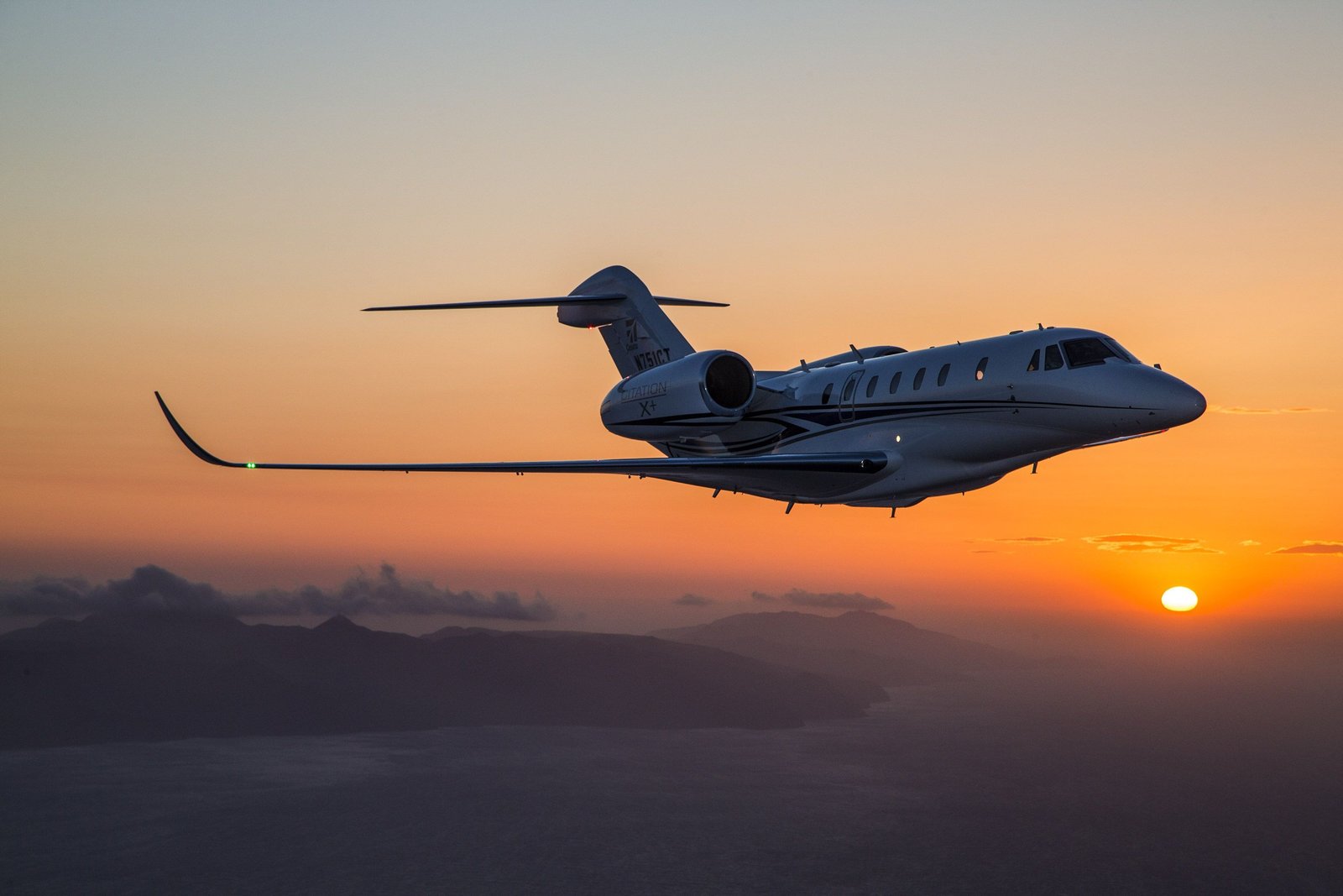 Aeronave ejecutiva en vuelo al atardecer con cielo anaranjado