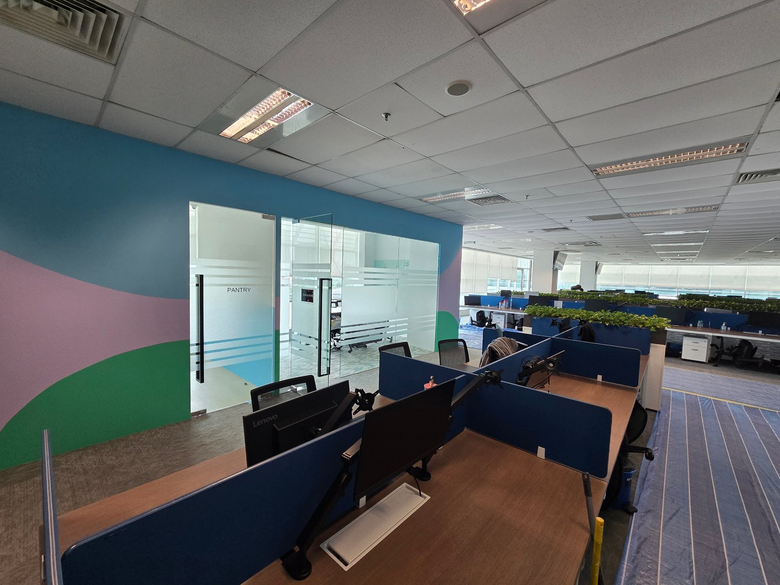 Wide view of Nasstar Cyberjaya open office with vibrant feature wall and blue desk dividers