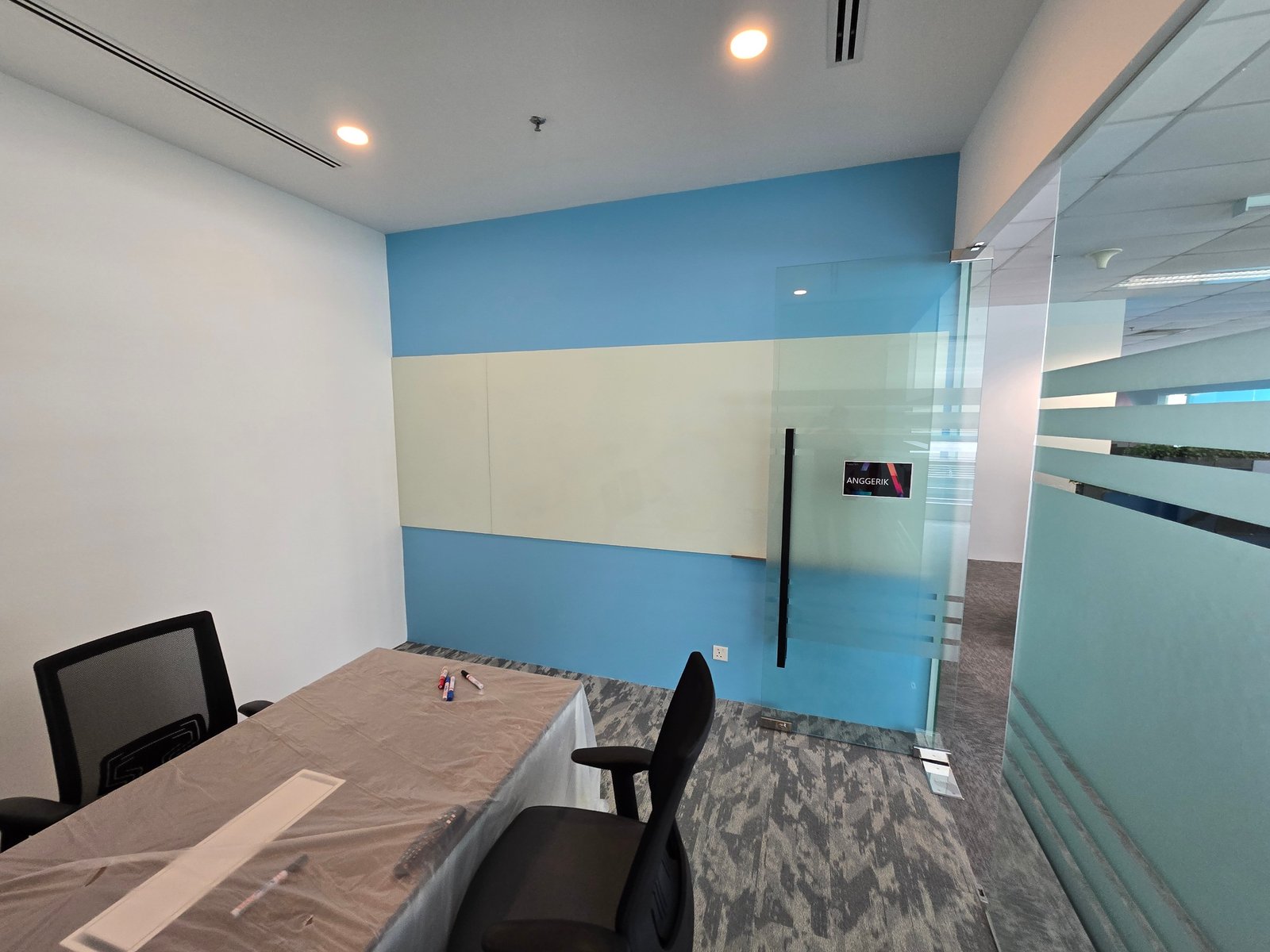 Anggerik meeting room at Nasstar Cyberjaya with blue accent wall, whiteboard and glass partition
