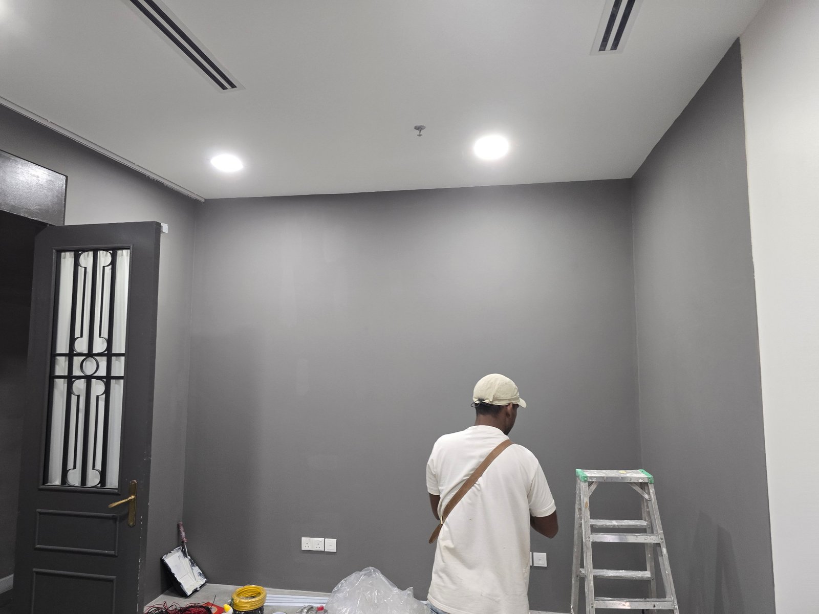Painter applying smooth grey finish to walls at GD Properties KLCC Showroom renovation